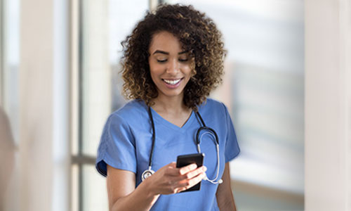 Young nurse in scrubs viewing mobile device.